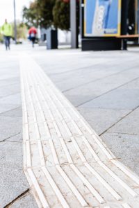 Il percorso guida tattile sul marciapiede, destinato all'orientamento dei non vedenti e degli ipovedenti, si snoda attraverso l'ambiente urbano.