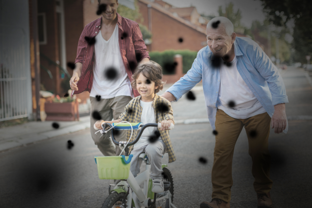 Otrok se vozi s kolesom, sliko prekrivajo temne lise in zamegljeni robovi (simulacija okvare mrežnice - citomegalovirusni retinitis).