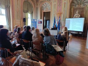 Udeleženci spremljajo osnovno usposabljanje o digitalni dostopnosti v zgodovinski predavalnici, predavateljica pa predstavlja vsebino ob projekciji.