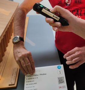 Oseba z elektronskim označevalnikom Penny Talks posluša razlago ob tipni maketi templja.